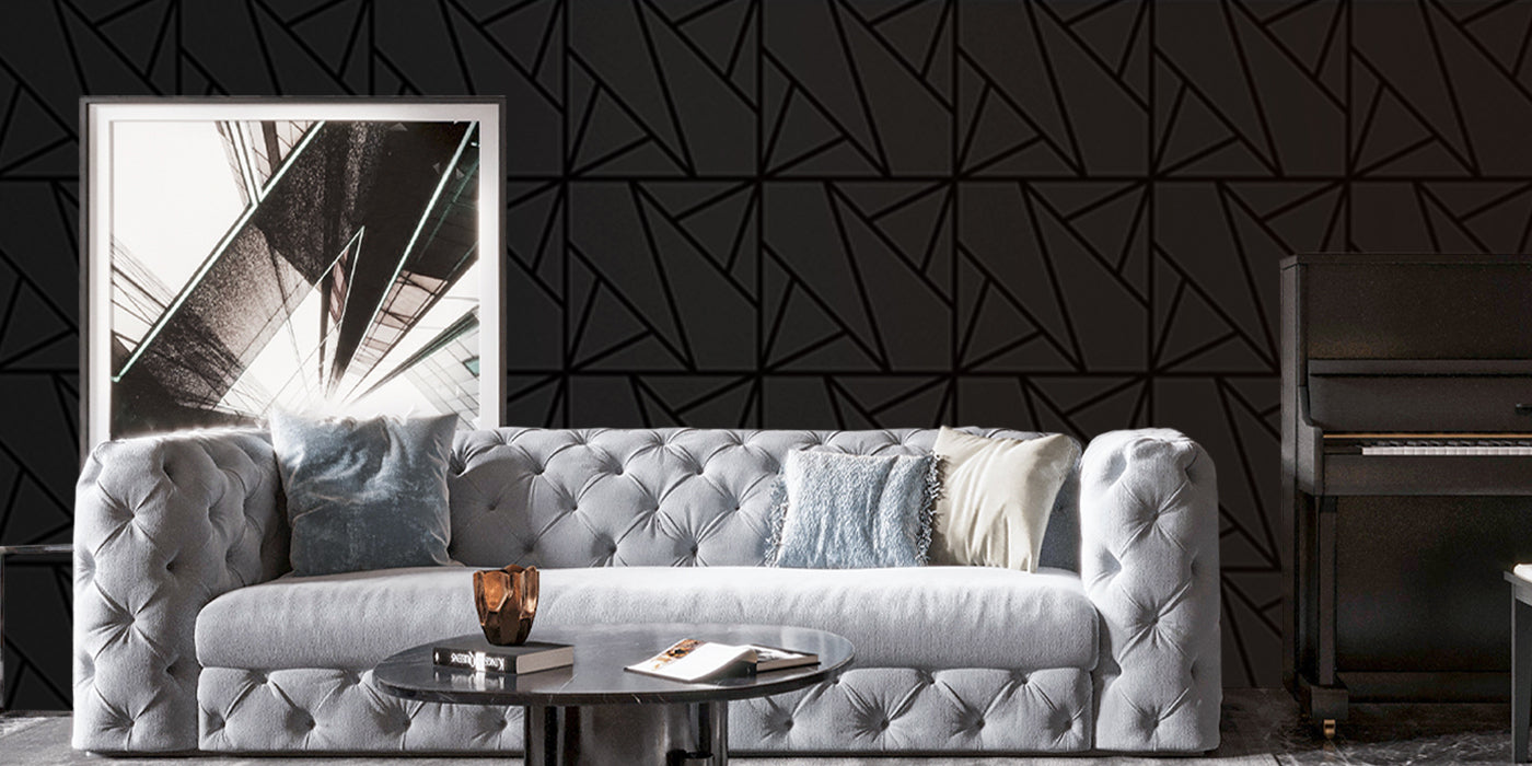 White tufted sofa with decorative pillows against a geometric black wall.